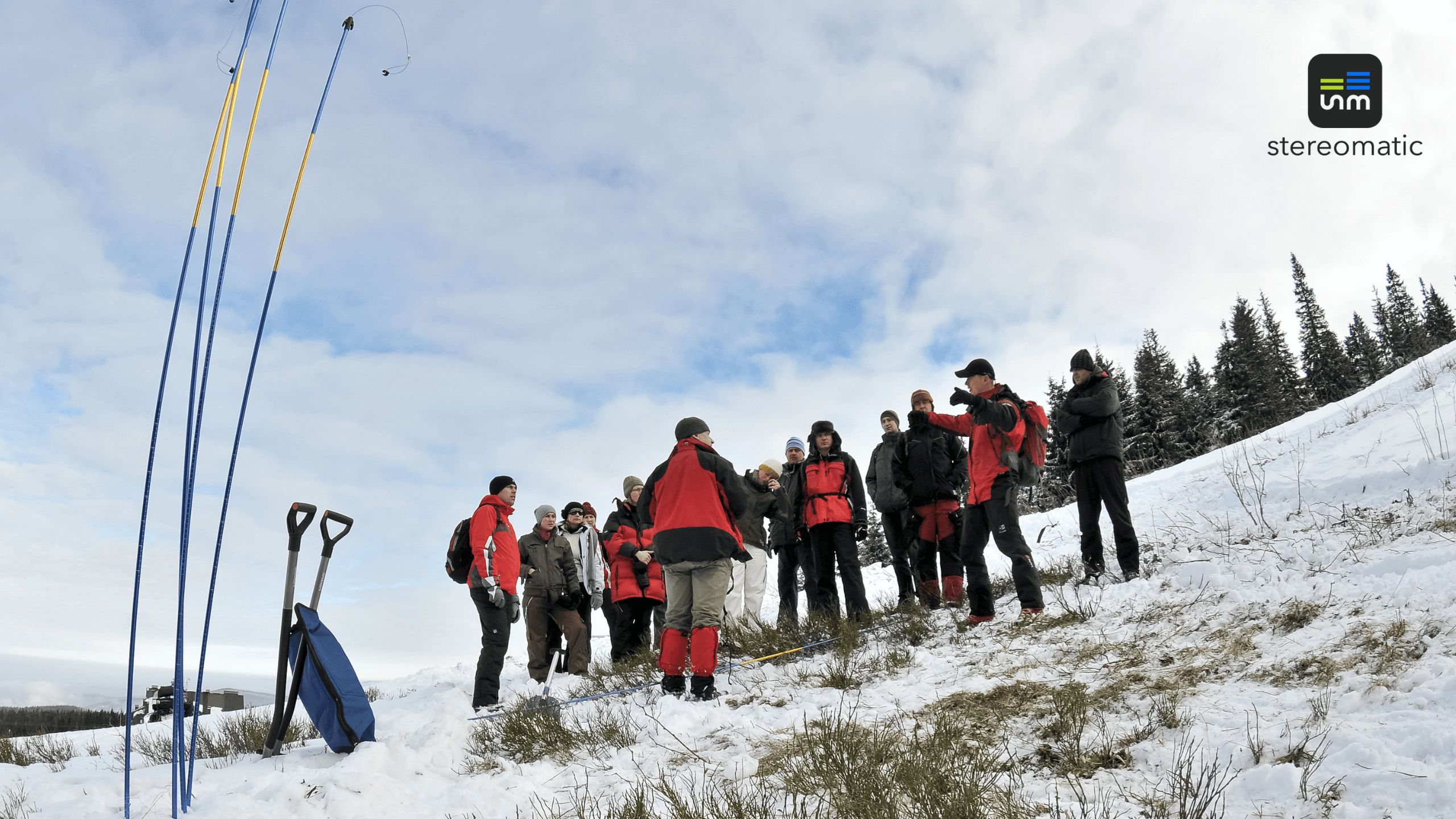 Zespół uczestników eventu CSR Skanska w górach, ćwiczący działania ratownicze z instruktorami GOPR na tle zimowej scenerii